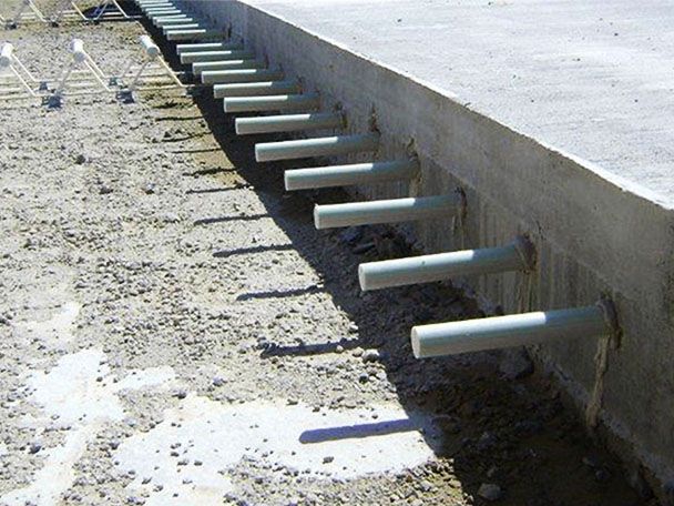Construction of a pavement extension showing round dowel bar protruding from the side of concrete slab.